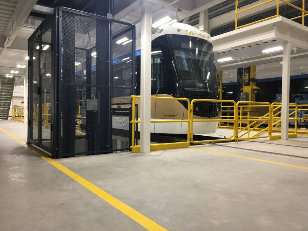 A PFlow vertical reciprocating conveyor being used alongside a bus