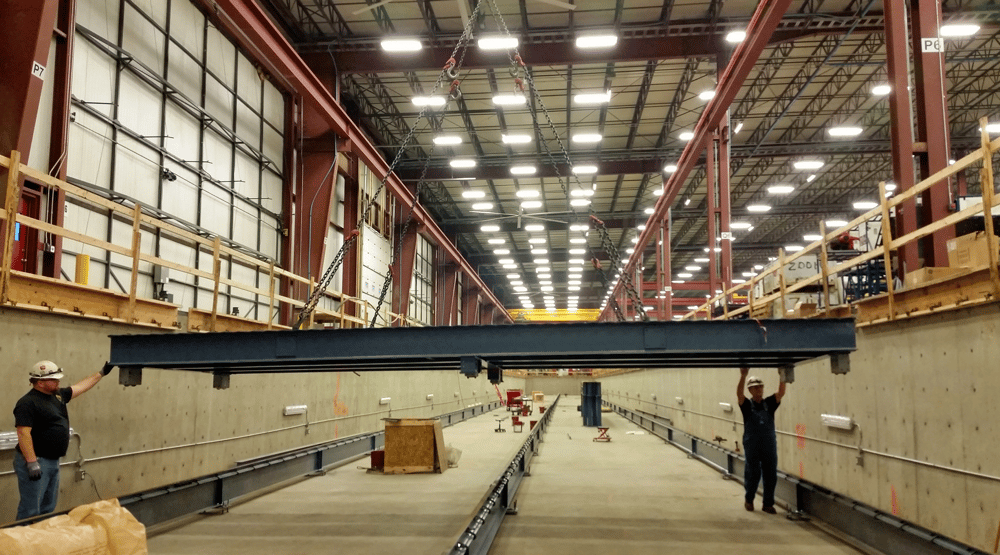 Construction workers install steel plates making a moving floor conveyor at Bourgault Industries agricultural machinery assembly facility in Saskatchewan, Canada.